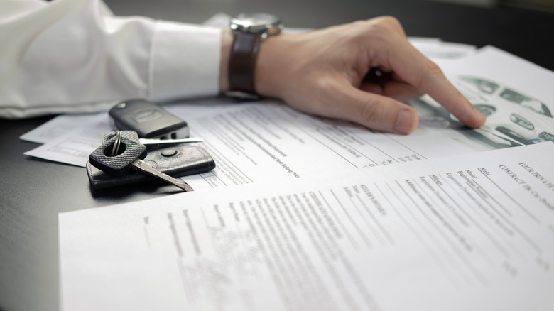 Hand and keys on car documents