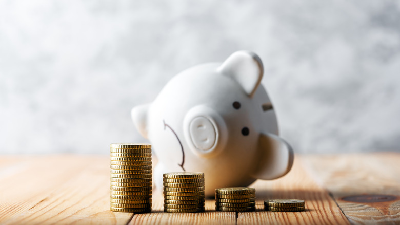 Sad piggy bank next to smaller coin piles