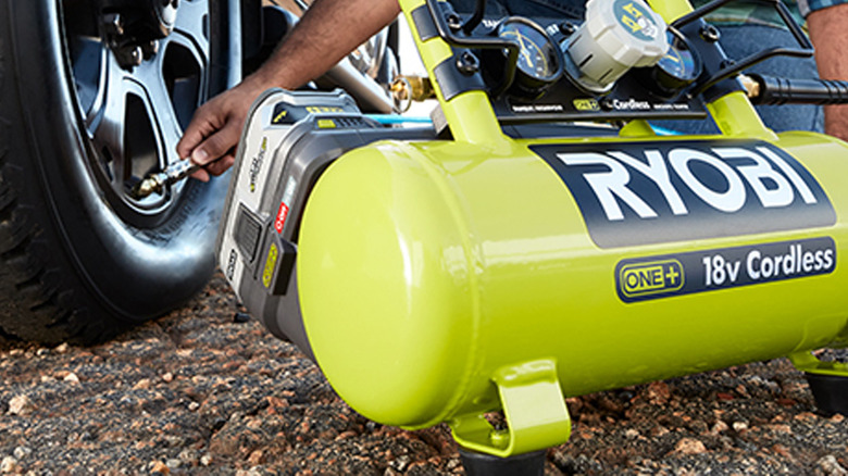 person using air compressor to fill tire