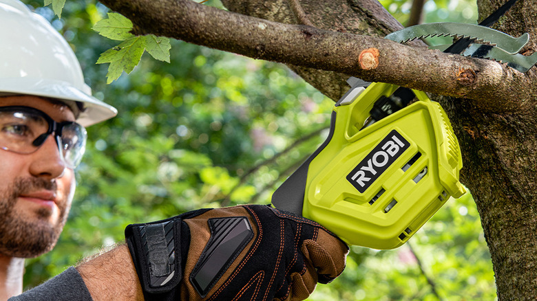 person using ryobi pruning saw