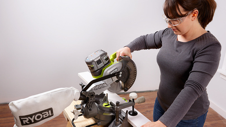 Woman cutting baseboard with Ryobi miter saw