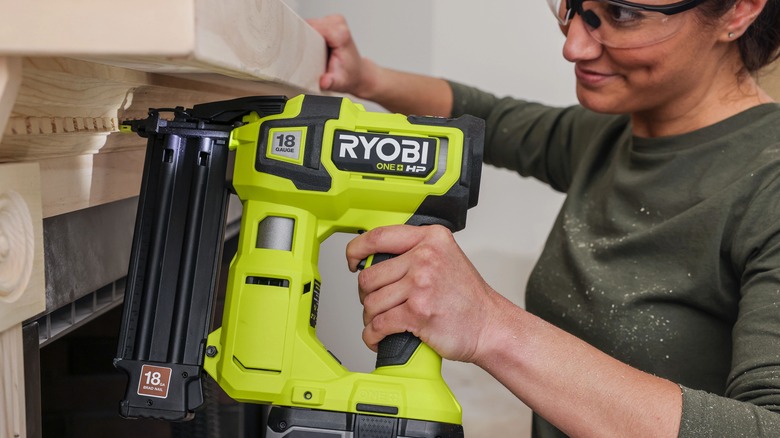 Woman using Ryobi nailer to install millwork