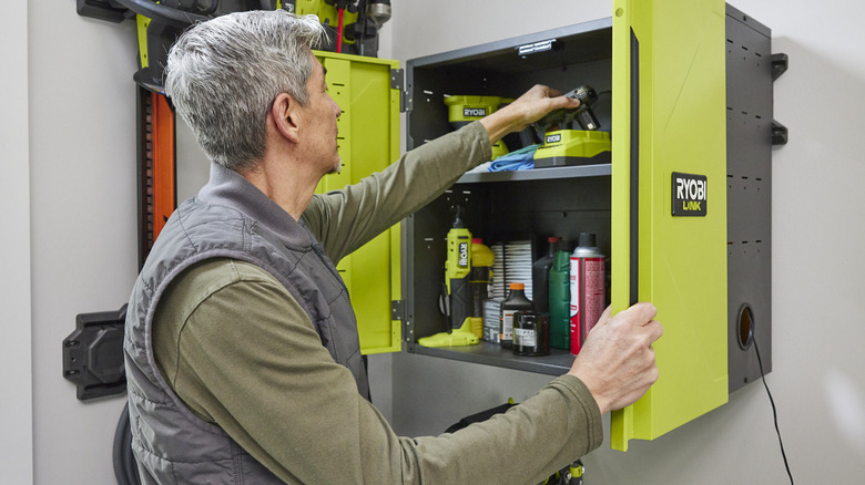 person grabbing tool Ryobi cabinet