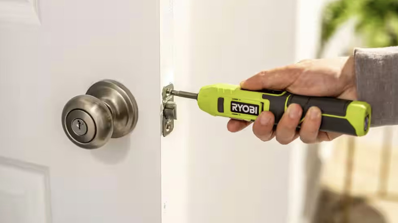 person using an electric screwdriver on a door