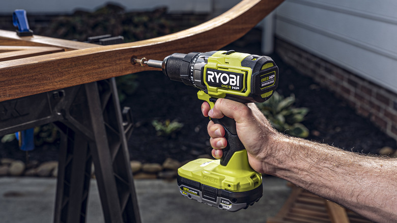 Hand using Ryobi drill driver to drill a screw