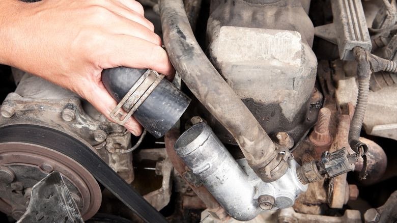 Person working on old radiator hose