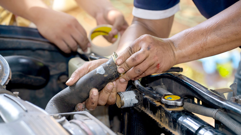 Person working on old radiator hose