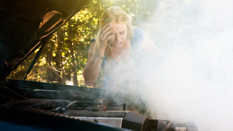 Woman looking at smoking overheated engine