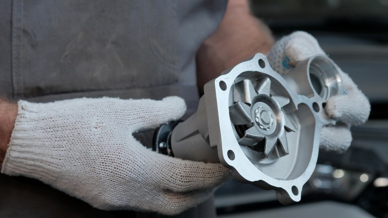 A person holding a new engine water pump