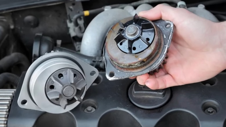 A person holding an old corroded water pump next to a new one