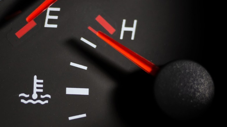 A car dashboard temperature gauge with the needle near the hot line