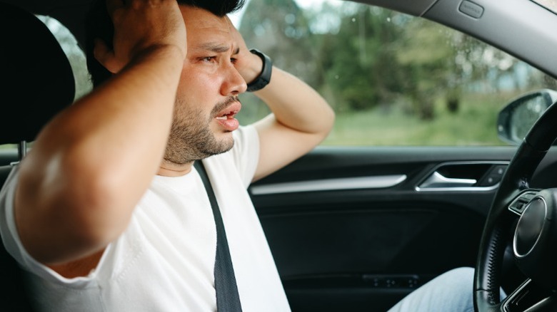 A surprised driver hearing strange noises from their engine