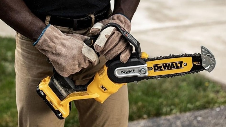 Man holding a DeWalt mini chainsaw