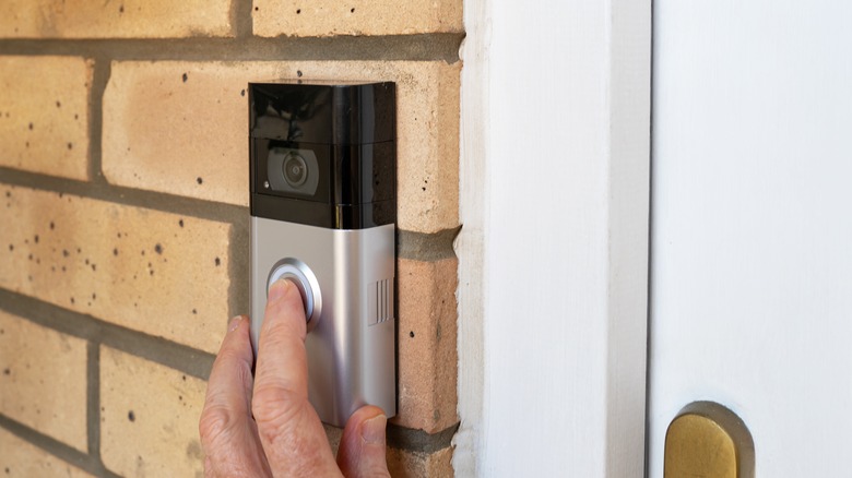 person's hand pressing smart doorbell