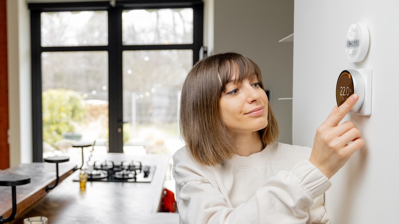 woman adjusting smart thermostat