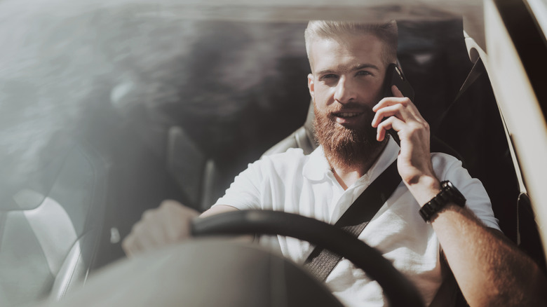 man holding phone while driving