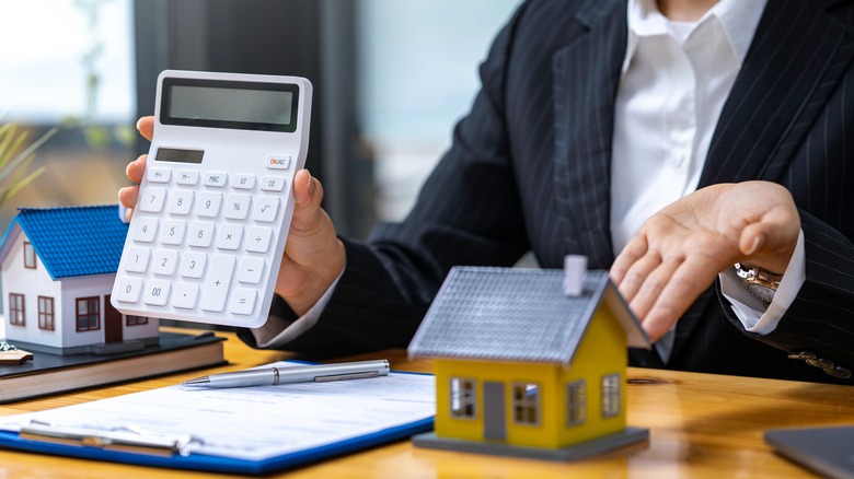 Real estate agent holds up calculator 