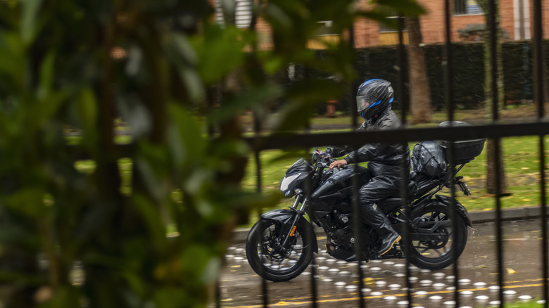 Riding motorcycle past gate