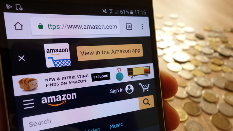Amazon website on smartphone with coins in background