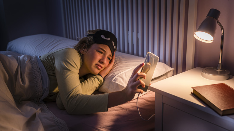 Woman in bed looking at phone