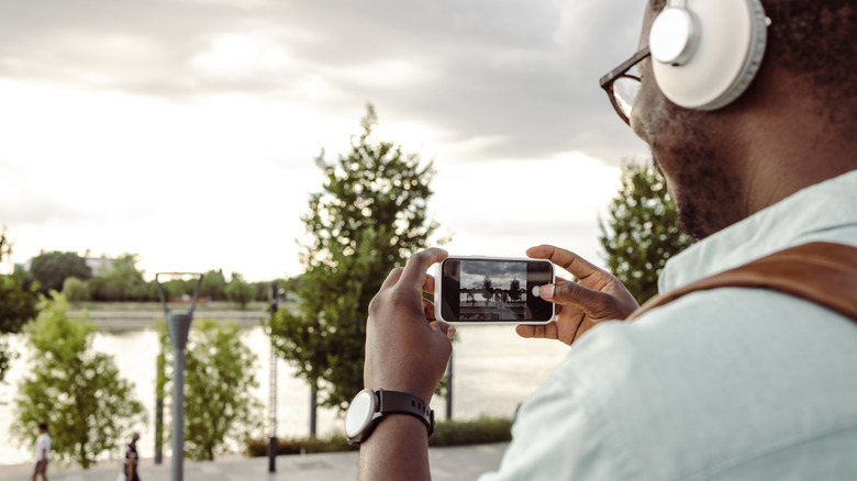 person recording river on smartphone