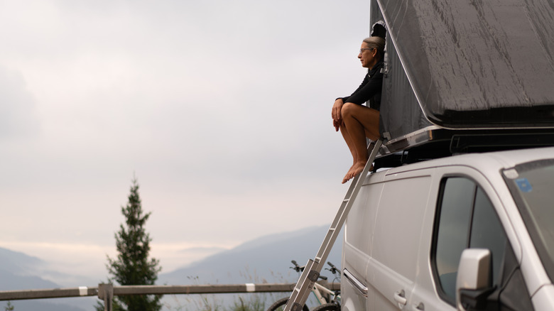 Woman sitting on van rooftop tent 