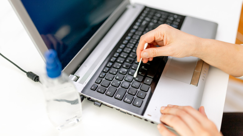 woman cleaning laptop with q-tip