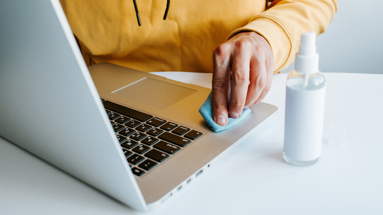 man wiping MacBook with cleaning cloth