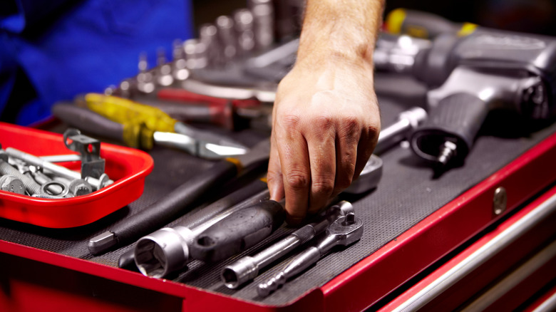 Man's hand grabbing a tool from his toolbox