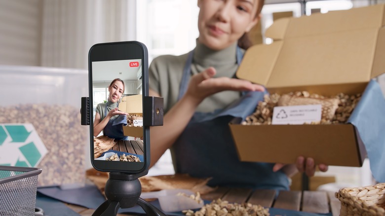 Woman taking video of herself with an open box