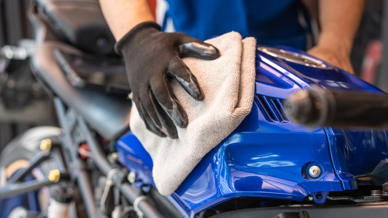 Person cleaning a motorcycle body with a rag