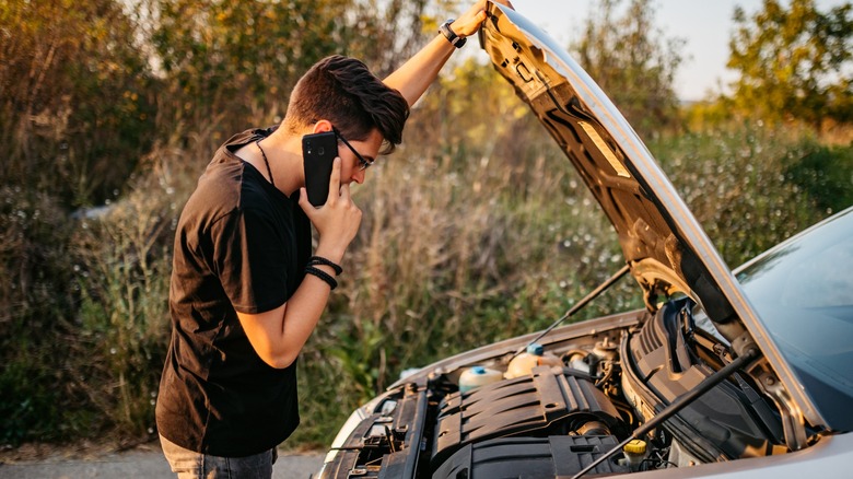 young person on phone with car hood raised