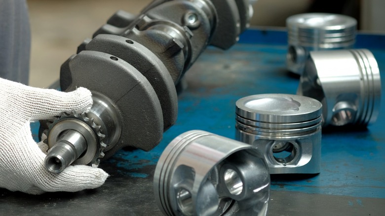 a person inspecting disassembled engine parts on a workbench