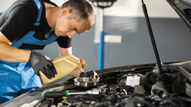 Man adding engine oil to a car