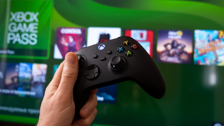 person holding Xbox controller with console UI in the background