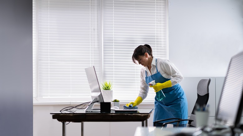 woman cleaning desk in office