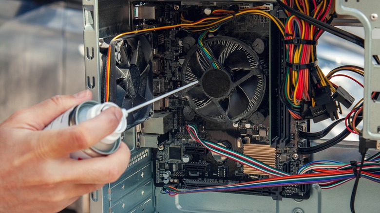 man using compressed air to clean dusty pc