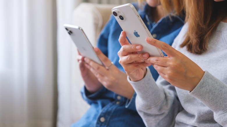 women holding iPhones close to each other