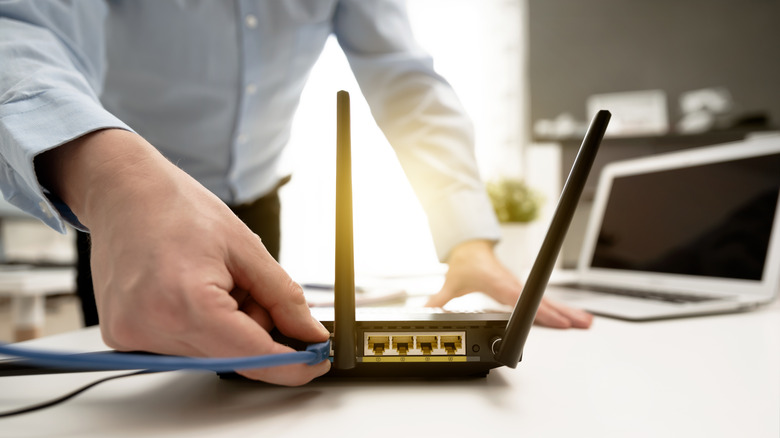 person plugging ethernet into router