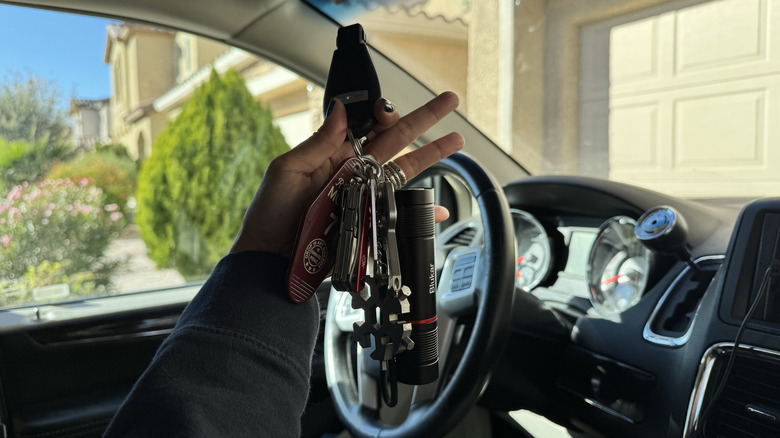 Author is inside a car holding up car keys that have several keychain tools attached to them