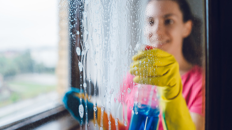 Woman cleaning window with glass cleaner