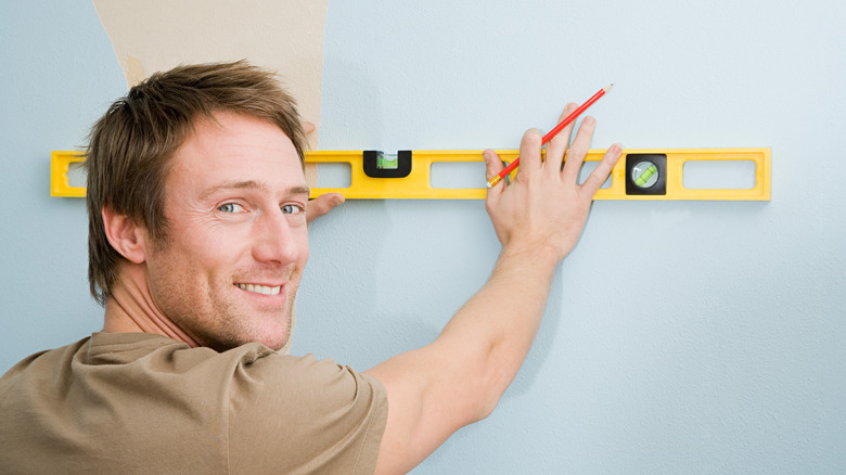 Man using level on wall