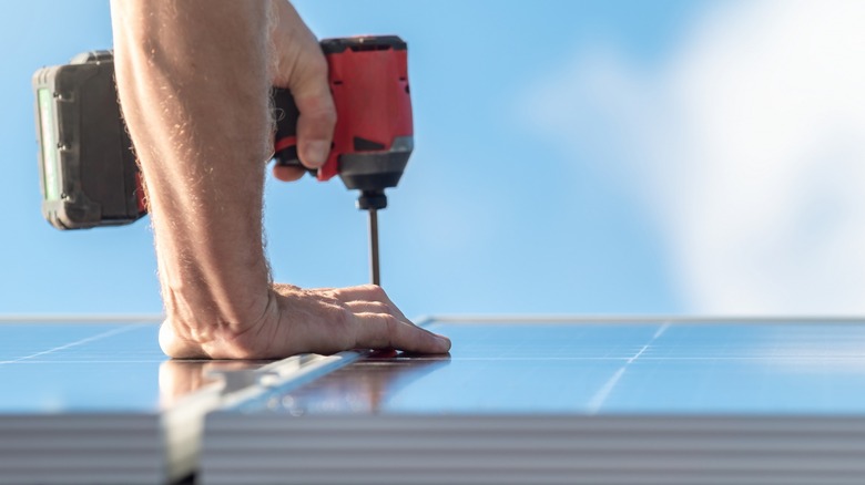 Person using cordless drill on solar panel