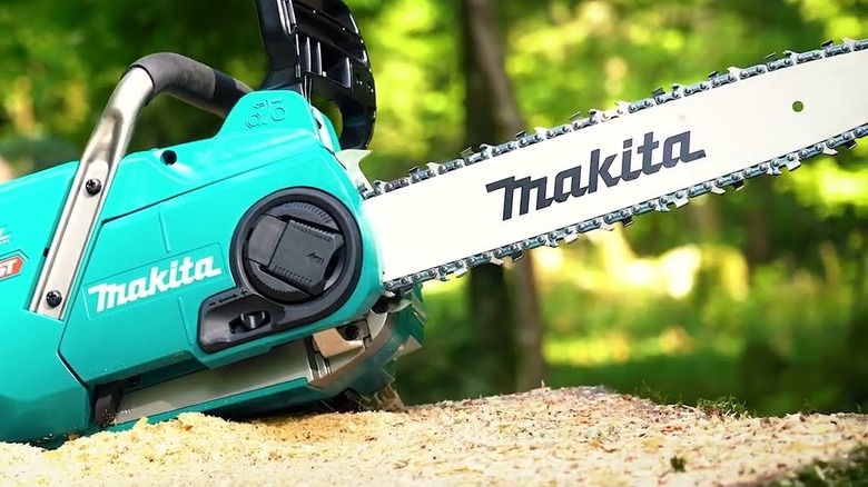 Makita chainsaw placed on the ground.