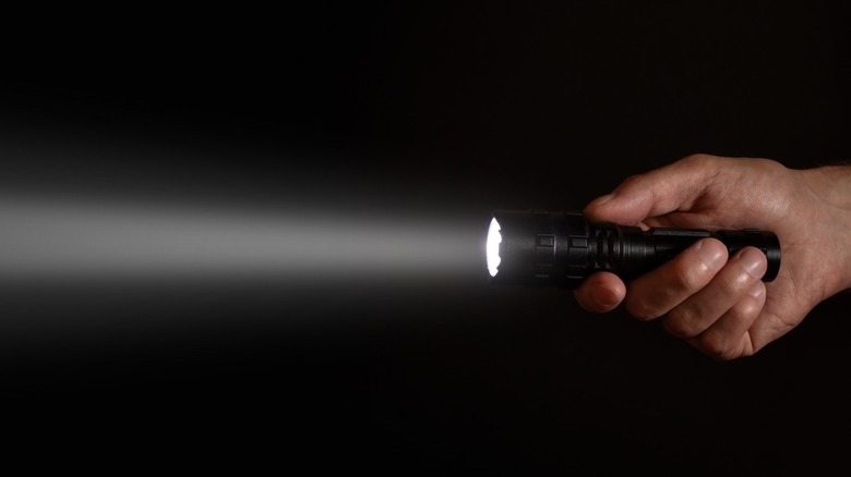 Handheld flashlight shining through darkness