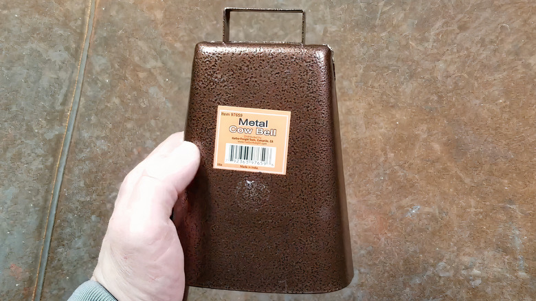 hand holding cowbell with sticker