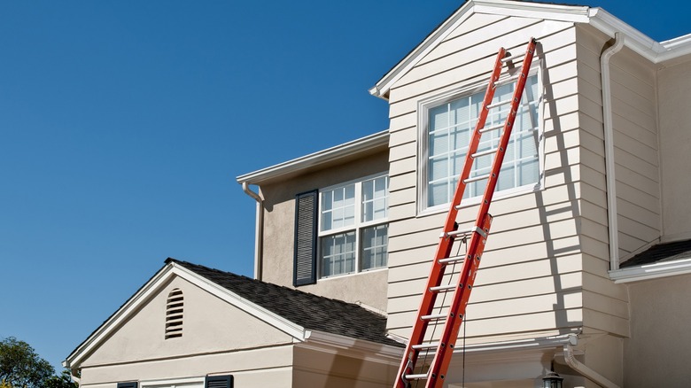 Tall red ladder leaning against house