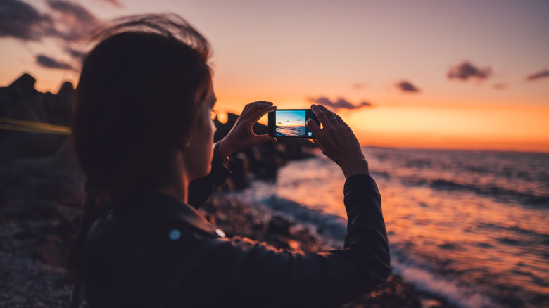 Woman taking sunset beach photo