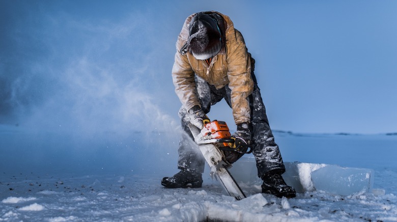 Person chainsawing through lake ice