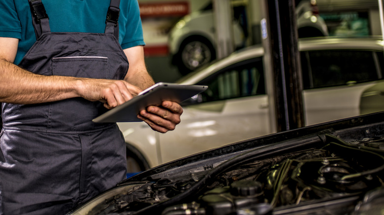 man analyzing car using tablet